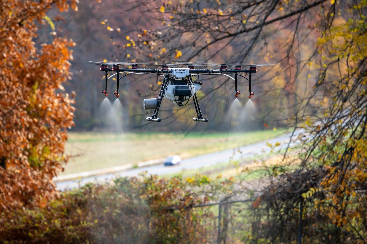 A drone flies in the air spraying pesticides.